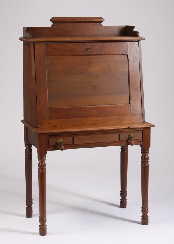 American drop front desk: Late 19th century American plantation drop front desk, the bracket shaped gallery surmounting the drop front, opening to drawers, pigeon holes, and filing, above a drawer, all raised on turned legs, 5