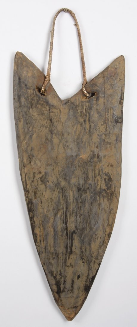 33"h chest shield, New Guinea Highlands: Chest shield, New Guinea Highlands, worn by a warrior in battle, the carved wood of tapered triangular form, attached to a braided cane support, contains traces of mud, charcoal, and natural pigments,