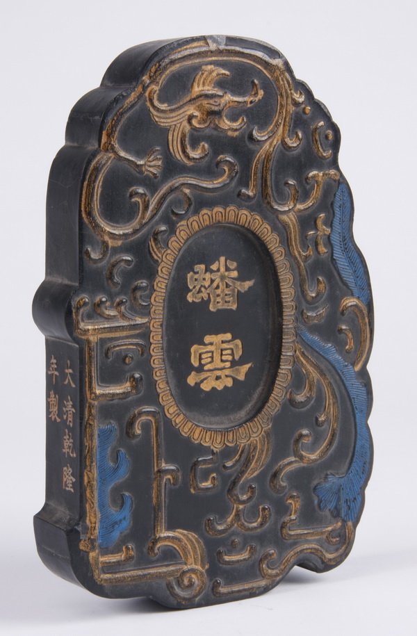 20th c. Chinese Imperial ink cake: 20th century Chinese imperial ink cake, parcel gilt with touches of polychrome pigment, moulded in shallow relief with a stylized dragon surrounding the central clerical script "Pan Yun" within an ova