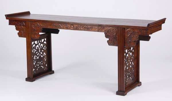 19th c. carved huanghuali Chinese altar table: Late 19th century Chinese carved huanghuali altar table, the rectangular top with everted ends surmounting a shaped apron, adorned with archaistic dragons in profile, including a pair of central confr