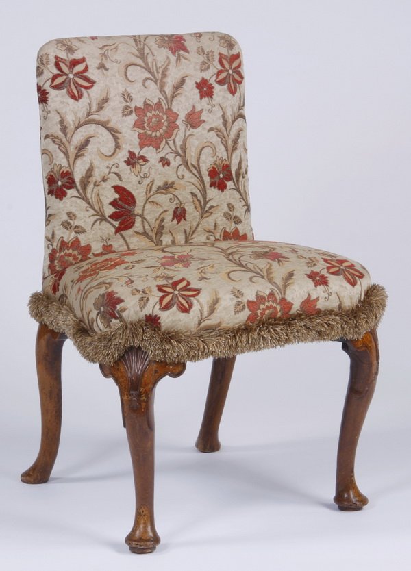 19th c. French slipper chair: Late 19th century French slipper chair, the back and seat upholstered in a red and champagne colored floral fabric with a fringe trim, raised on marquetry inlaid cabriole legs, 35"h x 24"w x 21"d.
