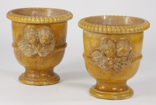 (2) French glazed earthenware jardinieres: Pair of 20th century French yellow glazed earthenware jardinieres, each of urn-form with a gadrooned rim and a central female bust surrounded by flowers, 22.5" h x 20" diameter.