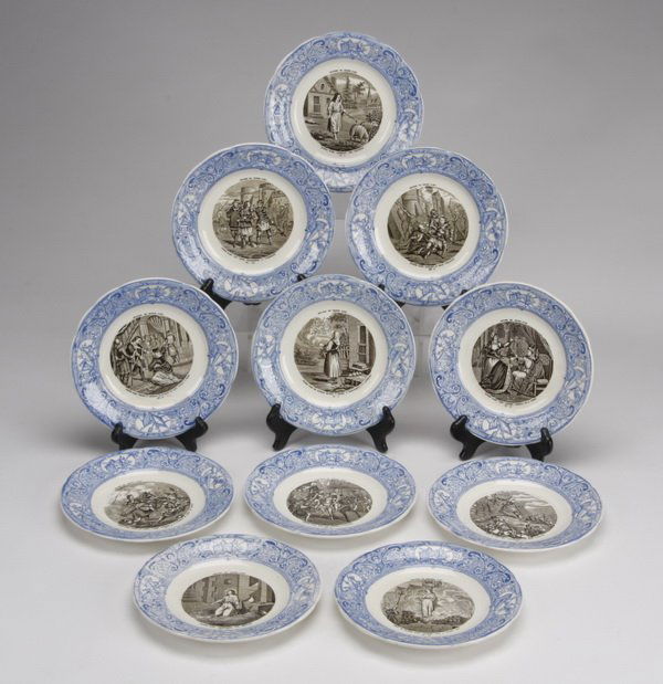 (11) French Gien porcelain plates: Set of eleven French Gien porcelain plates, each with an exterior and interior blue border enclosing a molded braid pattern and an applied scene from the life of Joan of Arc, each 7.5" diameter.