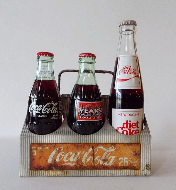 Mid 20th c. Coke bottle carrier w/bottles: Aluminum Coca-Cola six bottle carrier, circa 1950s, marked "Property of the Coca-Cola Bottling Plant", 7"h x 8"w x 5.5"d; together with three Coca-Cola commemorative soda bottles including "Introducin