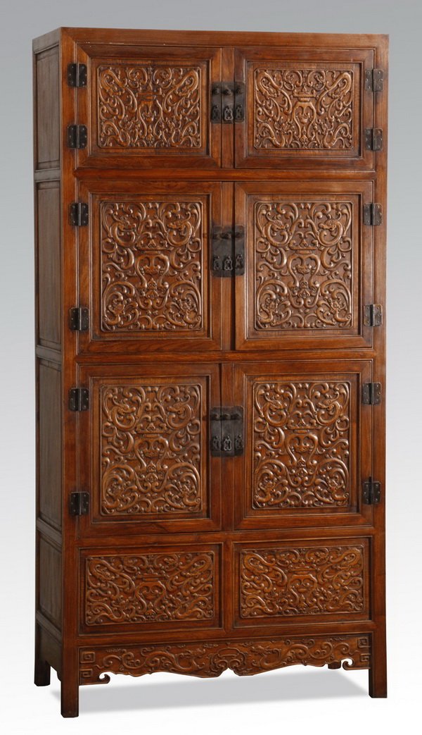 Early 20th c. Chinese huanghuali cabinet: Early 20th century Chinese huanghuali cabinet, ornately carved in low relief with dragons meandering through scrollwork, having a series of three double-door cabinets opening to storage surmounting de