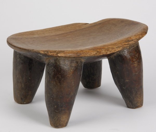 Lobi stool, Mali, Ivory Coast: Lobi stool, Mali, Ivory Coast, intended to be used by a woman while working, carved from a single block of wood, with the concave seat supported by four tapering legs, 6.75"h x 12.5"l x 8"w.