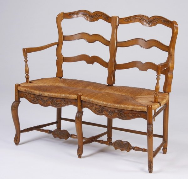 French Provincial style walnut settee: 20th century French Provincial style carved walnut ladder-back two-seat settee, the floral carved frame surmounting a woven rush seat with a carved floriate apron, raised on cabriole legs joined by H-