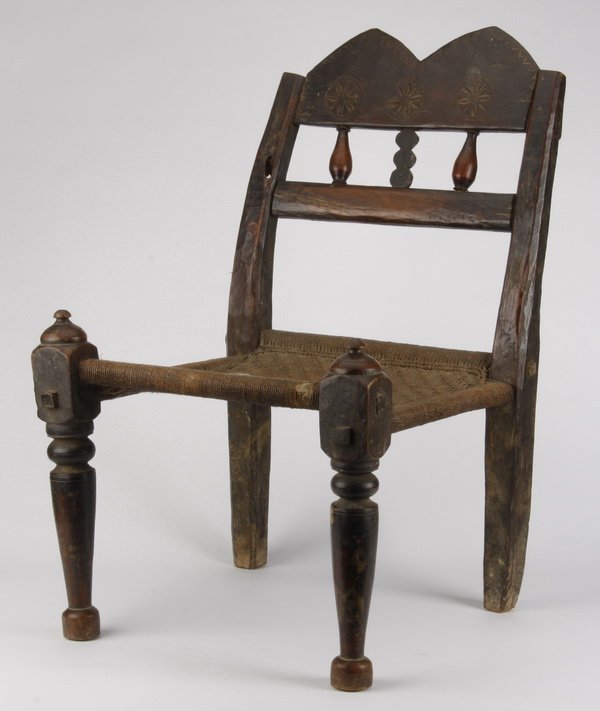 Rare Nepalese carved chair: Rare Nepalese carved chair, the triangular ridge crest with incised medallions, over a woven rope seat, raised on tapering turned and block legs 28.5"h x 18"w x 17"d.
