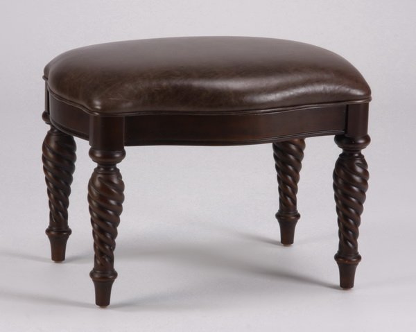 Leather ottoman with turned legs: Traditional style ottoman upholstered in chocolate brown leather, the serpentine shaped hardwood frame with four turned legs, 19"h x 24"w x 19"d.