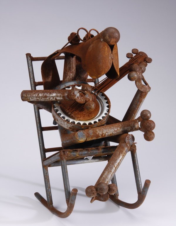 Folk art iron sculpture: Mid to late 20th century folk art iron sculpture, in the form of a dog wearing glasses, seated in a rocking chair and playing the banjo, 17.5"h x 14"w x 11.5"d.