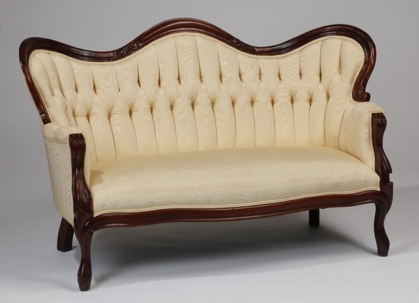 Victorain style settee: Carved Victorian style settee, mid to late 20th century, the serpentine button tufted back surmounting a singular long seat, all upholstered in a cream color fabric, raised on curved and cabriole legs
