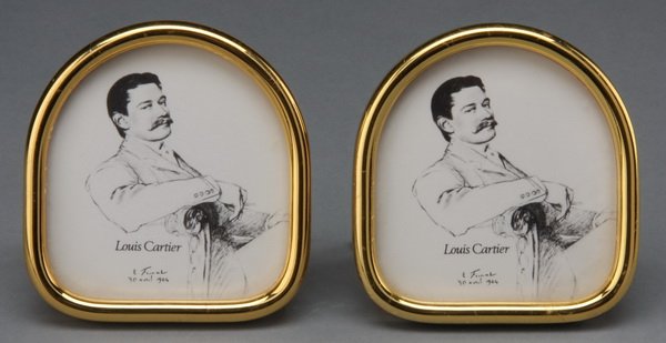 (2) Petite les must de Cartier picture frames: Pair of Les Must de Cartier petite picture frames in brass with enamel accents, of ovoid form, with three small cabachon sapphire screws on the back, the easel style back terminating in "C" Cartier lo