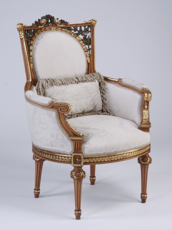 Louis XVI style carved, parcel gilt bergere: Louis XVI style carved and parcel gilt bergere, the curved frame with allover braided detailing and a central pierce carved polychrome ribboned wreath at the backrest, the tight back and seat cushions