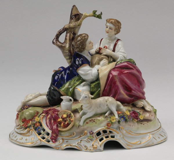 19th c. German porcelain figurine, marked: Late 19th century German hand painted porcelain figurine depicting a courting couple in a picnic setting with fruit, wine, and a lamb resting on the base, marked blue crown, incised crown mark Schierh