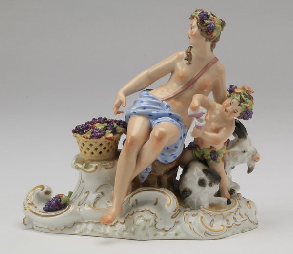 19th c. KPM porcelain grouping, marked: 19th century KPM hand painted porcelain figural grouping depicting a maiden and putto celebrating the harvest with clusters of grapes in their hair, the putto pouring wine and seated on a spotted goat