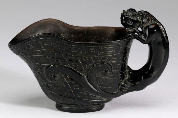 Chinese carved obsidian wine cup, 3"w: Chinese carved obsidian wine cup with figural handle, of helmet-form with incised geometric decoration, 3"h x 4.5"w.