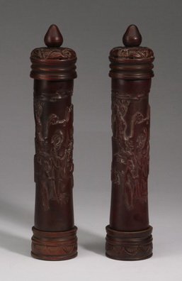Chinese carved wood incense tubes, 12"h: Chinese carved wood incense cylinder tubes, the lids with fruit form finials above bodies carved with scenes depicting men in landscapes of pine and wisteria, the bases having a band of lotus leaves, 