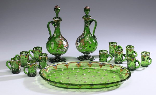 14-Piece cordial set, A.A. Egermann: 14-piece Bohemian enamel decorated emerald green glass cordial set by Anton A. Egermann, comprising (2) diminutive ewer form decanters having stoppers, surmounting long necks, above the bulbous bodies