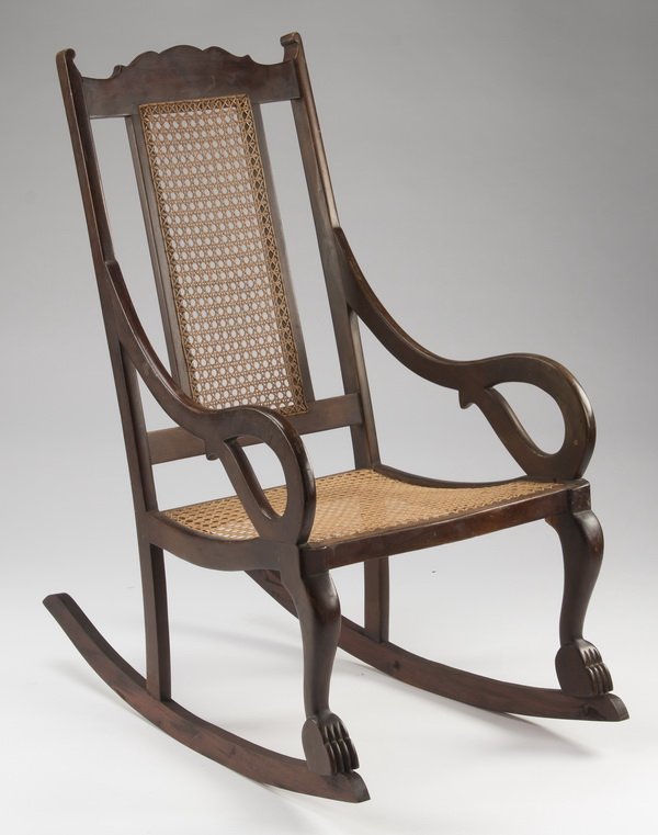 West Indies style mahogany & cane rocking chair, 39"h: West Indies style mahogany and cane rocking chair, having a shaped crest above an inset cane panel, leading to scrolled arms above a caned seat, rising on stylized cabriole legs terminating in paw fee