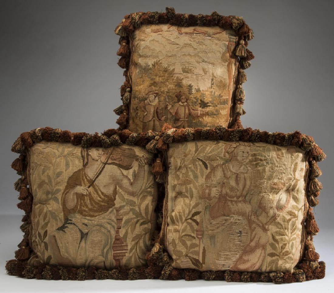 (3) Custom made Aubusson tapestry fragment pillows: Three 18th century French Aubusson tapestry fragments crafted into custom throw pillows, each with velvet backing and fringed cording, motifs include a figural pastoral scene, a maiden playing a violi
