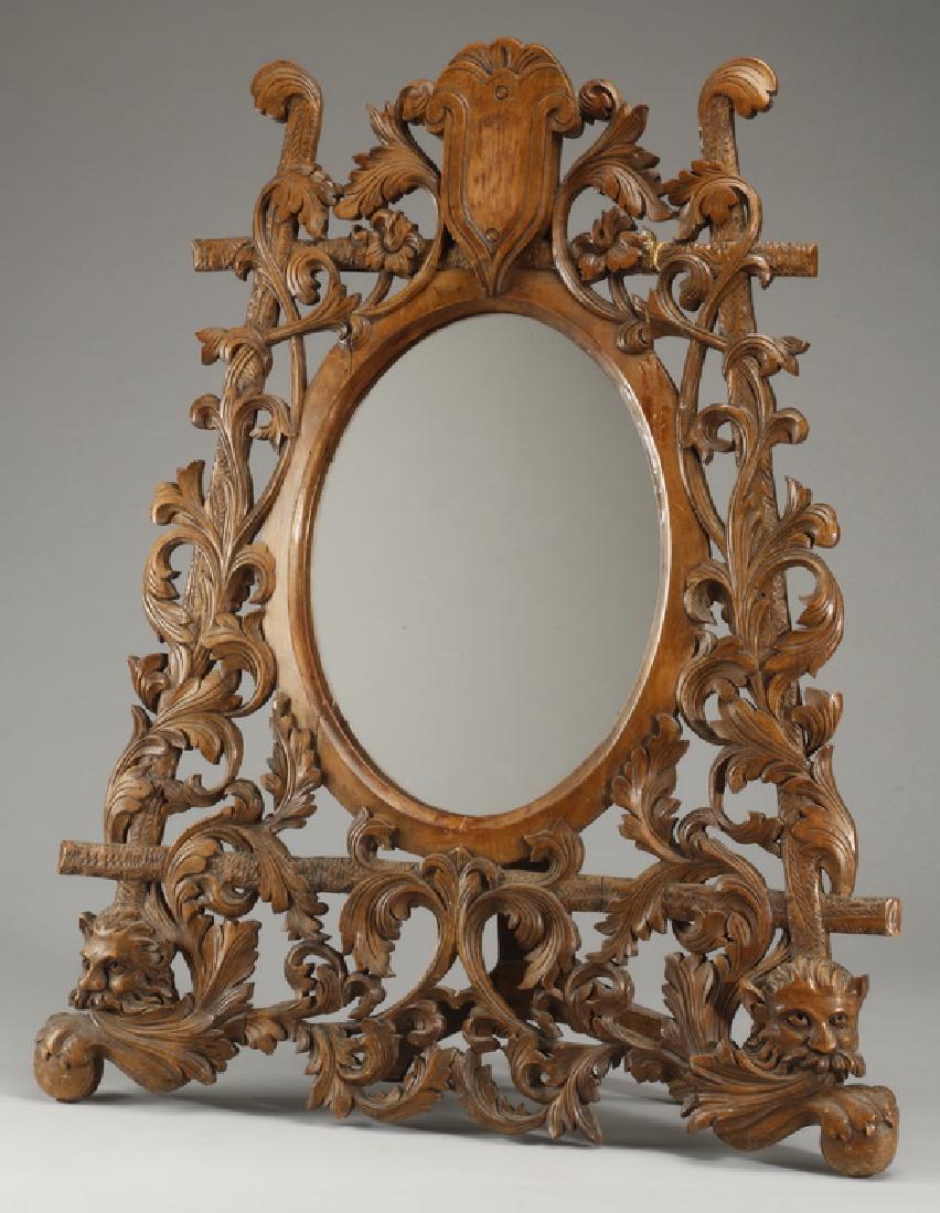 19th c. French carved walnut vanity mirror, 34"h: Late 19th century French Rococo style pierce carved walnut dressing table mirror, having a shield crest surmounting the foliate entwined branch frame, surrounding the oval-shaped mirrored glass, 34"h 