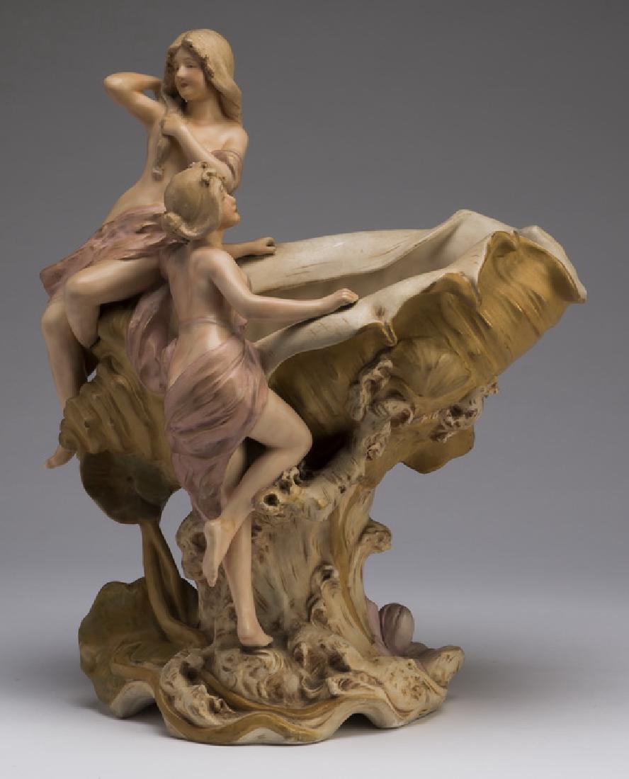 Royal Dux Art Nouveau figural centerpiece: Art Nouveau figural centerpiece, Royal Dux Bohemia, early 20th century, depicting two semi-nude maidens, one climbing a conch shell, the other perched on top, resting on a stylized naturalistic base, 