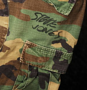 Sex Pistols / Steve Jones: signed camouflage cargo: Sex Pistols / Steve Jones: previously personally owned and stage worn camouflage cargo pants, the green and brown camouflage trousers autographed in black marker by Steve Jones, worn during the