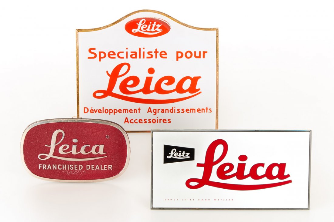 E. Leitz Advertising (Lot): three rare Leitz advertising displays in very fine condition, (1) Leitz Leica glass advertising, 15x29cm, (2) 24.7x27.8cm glass advertising 'Leitz Specialiste pour Leica Dèveloppment Agrandissements 