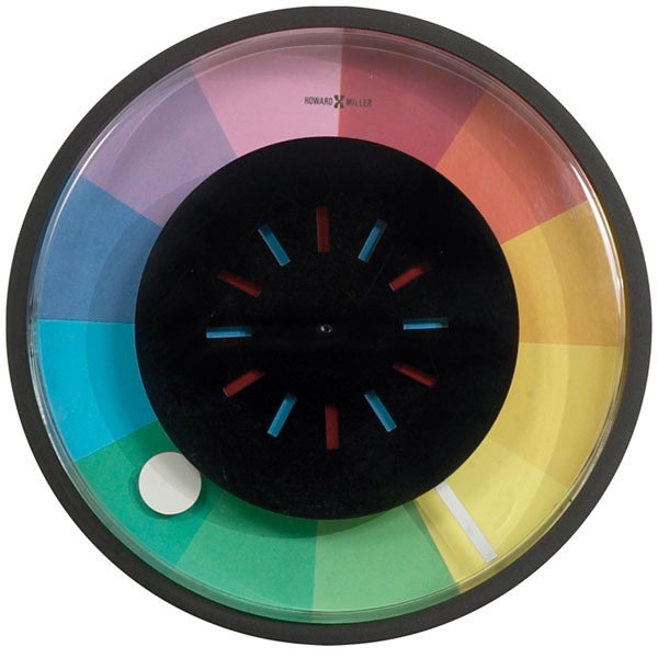 Howard Miller clock, rotating wheel rainbow-colore: Howard Miller clock, round black plastic case with rotating black enameled metal center wheel over a rainbow-colored face, wheel rotates to reveal blue and red colors, white hour and minute hands, sig