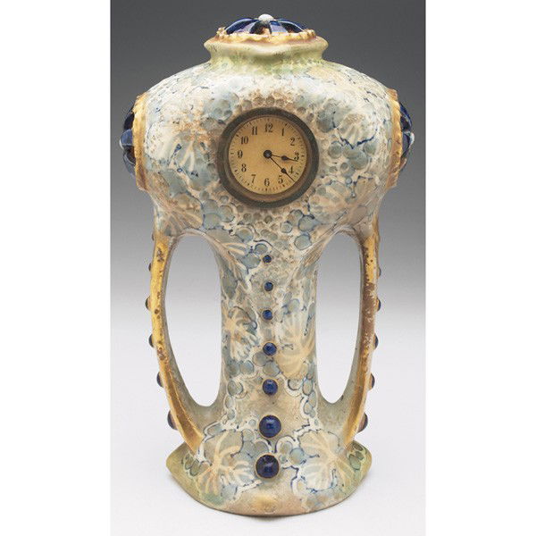 Amphora clock, double handled shape with painted g: Amphora clock, double handled shape with painted gray and blue leaves and berries, applied blue stones, gold accents, basic clock face on one side, marked, #11685, 7"w x 11.75"h, this clock is picture