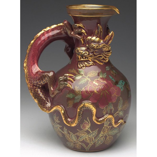 Zsolnay handled vessel red glaze: Zsolnay handled vessel, Asian inspired motif with a sculpted dragon handle and a painted floral design, covered in a red glaze with gold accents, marked, 8"w x 10.5"h