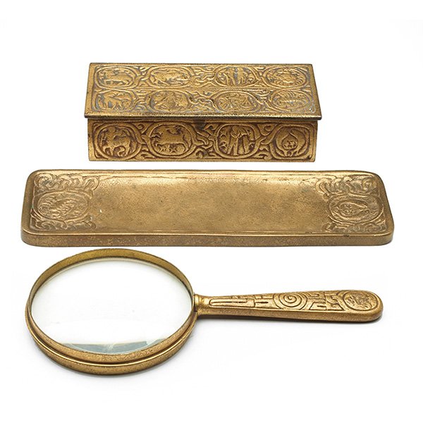 Tiffany Studios desk items: Tiffany Studios desk items, magnifying glass, #928, 9"l; tray, #1009, 10"l; box, #811, 7"w, all bronze in the Zodiac pattern, all with an original gold dore patina, all signed Tiffany Studios, New Yor