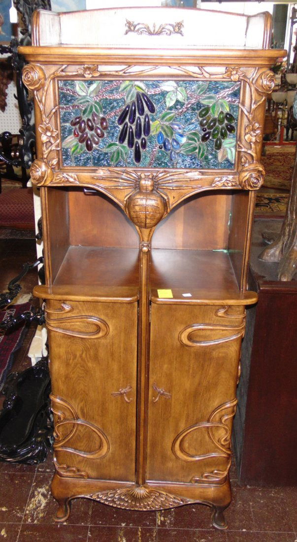 Art Nouveau Style Wine Bar Cabinet: Art Nouveau Style Wine Bar Cabinet with back lit Stained Glass Panel. Great carving. Wine glass holders in mid section. Bottle storage on the bottom. Measures " tall x " wide. Condition is very good.