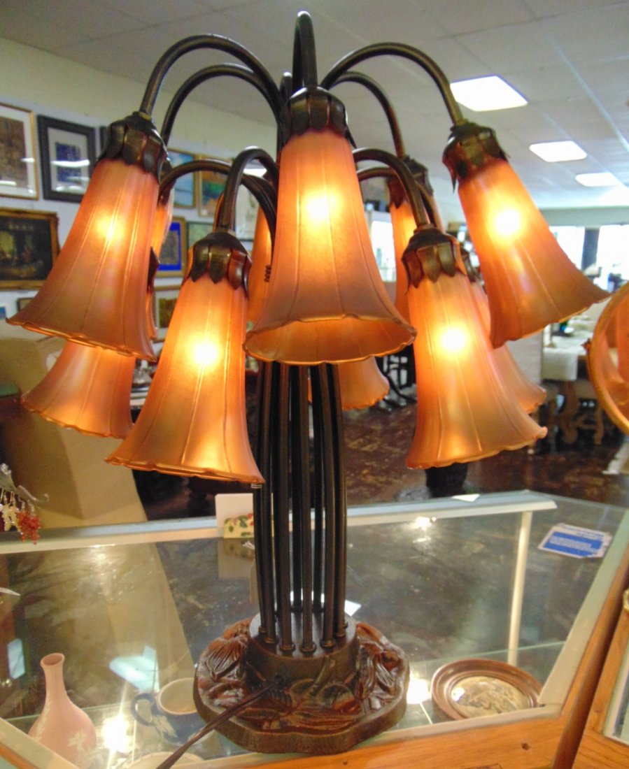 Tiffany Style 12 Light Lily Table Lamp: Tiffany Style 12 Light Lily Table Lamp. Measures 20" tall x 21" wide. Overall condition is Good with the exception of one broken shade. As-is. Several Shipping Options Available. Starting Bid $100. Au