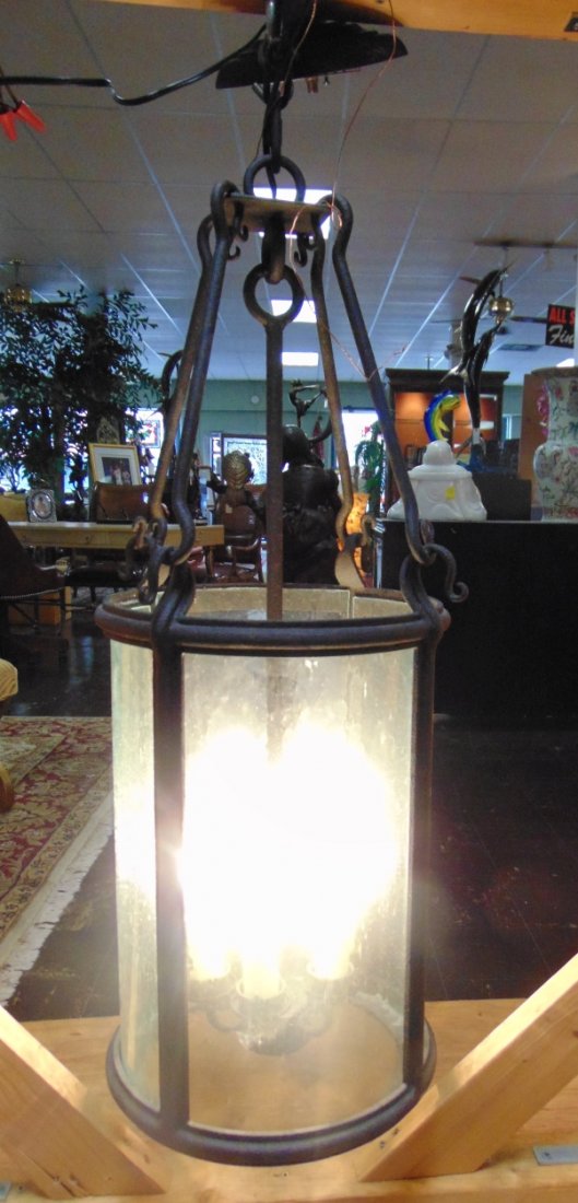 Black Wrought Iron Hanging Light Fixture: Heavy Black Wrought Iron Hanging Light Fixture with textured glass. Indoors or Outdoors. Measures 36" tall x 14" wide. Overall condition is good with minor wear. Several Shipping Options Available.