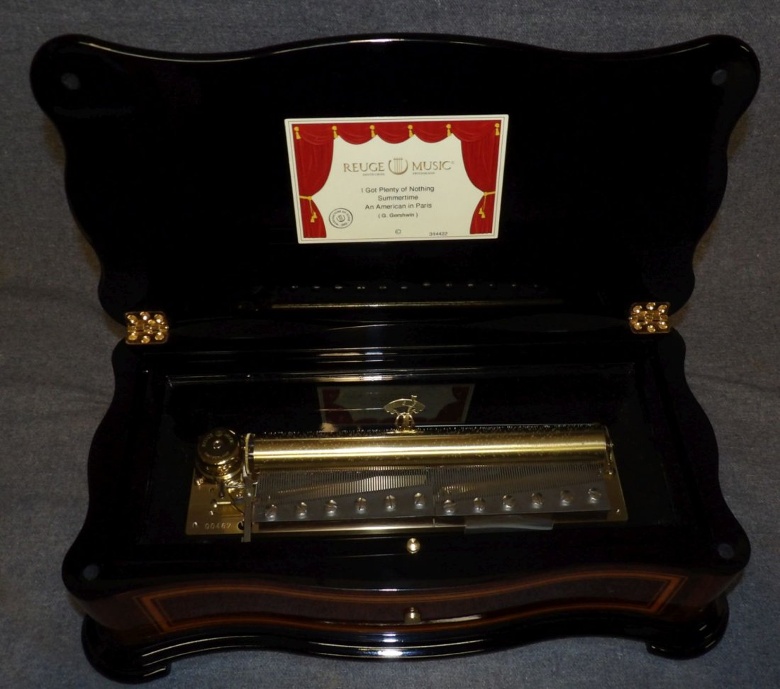 REUGE CYLINDER MUSIC BOX: Reuge Inlaid Cylinder Music Box. Hand crafted in Switzerland. Works perfectly. Measures 5-1/4" tall x 15-3/4" wide x 8-1/2" deep. Condition is Excellent. Mint. No damage. Starting Bid $1,000. Auction 