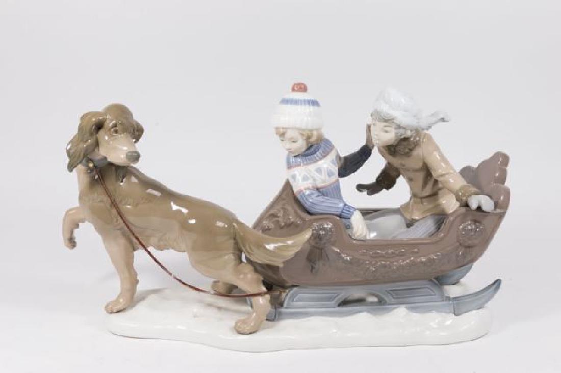 :Lladro "Sleigh Ride" #2349M: Boy and girl in a sled being pulled a Spaniel-type brown dog. Dog has leather rein attached to sled. Approx. 10" H x 18" W. (5037) Good condition.