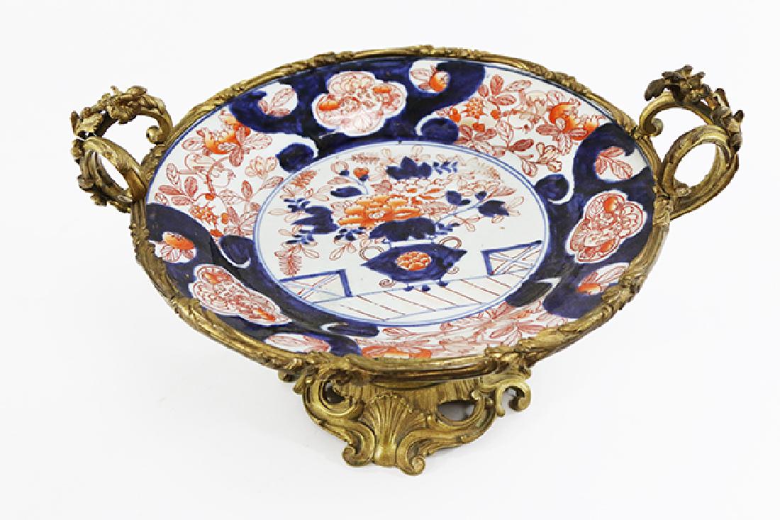Imari Charger on Bronze Stand: Blue, white, and orange. Floral design. Approx. 8" H x 15" W.