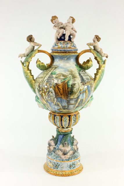 Majolica Soft Paste Porcelain Covered Urn: 19th century. With cherubs and dolphin. Approx. 38" H x 20 1/2" D. Dolphin as is.