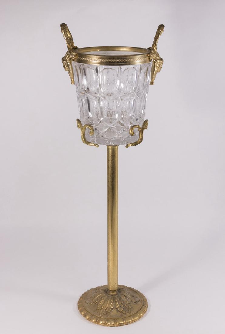 Bronze Mounted Glass Champagne Bucket: On stand. Bucket with figural handles. Approx. 11" H x 10" W with handles, 30 3/4" H with base.