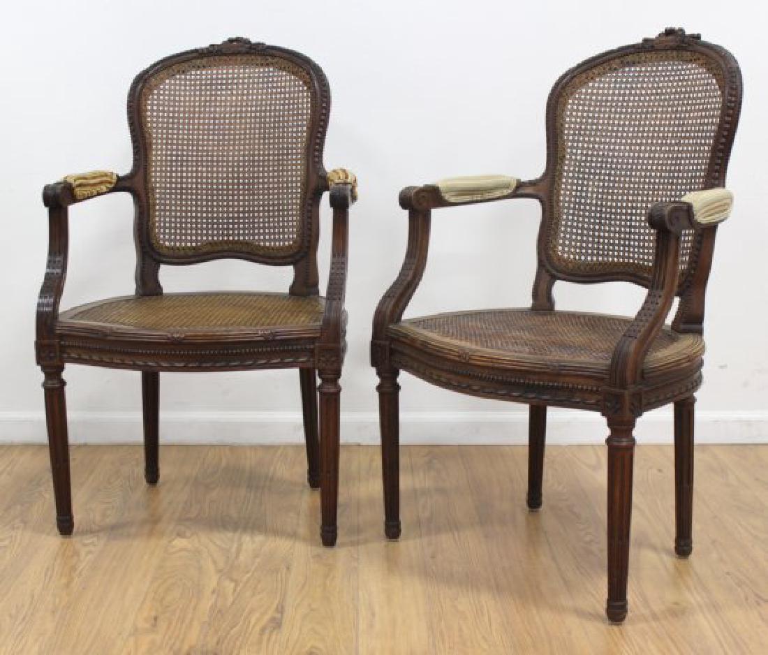 :Pair Louis XVI Style Carved Walnut Fauteuils: Cane back. Cane seat. Gadroon carved all around. Musical instrument and rose design on top. Green upholstered armrests. Approx. 39" H x 23 1/2" W. (6096) Cane in good condition.
