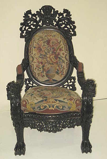 Oriental antique highly carved chair: Possibly rosewood with pierced carved crest, hips & skirts, carved arms with foo lion terminals above claw footed supports & floral needlepoint upholstery. Approx. 48" H x 29" W x 32" D.