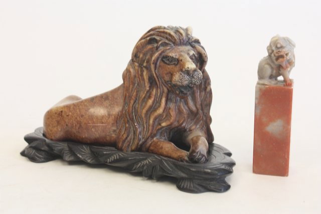Soapstone "Reclining lion"& "Foo Dog" stamp: Carved soapstone. 2 pieces. Lion is on teakwood stand. Approx. 6" x 3.25", stand 3.75". Please read our terms of sale.