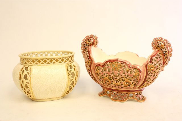 Lot of 2 Zsolnay centerpieces: 1- Yellow reticulated vase, approx. 5.25" x 7.5" W. 1- Pink reticulated 2 handle centerpiece, approx. 7.5" H x 10.5" W. Please read our terms of sale.
