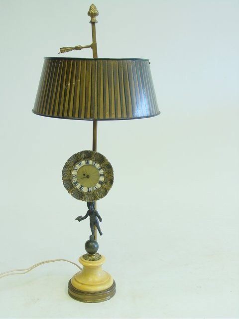 19th c. Bouliotte lamp: Figural stem supporting a clock, with tole shade. Approx. 25.5" H Please read our terms of sale.