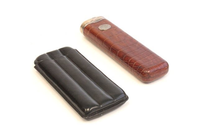 Group lot of cigar boxes: 1- Sterling & alligator cigar box, hallmarked for Birmingham, England, approx. 6" x 1.5". 1- Black leather 3 cigar box, approx. 5.25" x 2.5". Please read our terms of sale.
