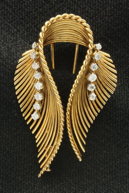18kt yellow gold clip with twin feathers: With 14 diamond chips. Approx. 1.65 carats, 13.1 dwts.