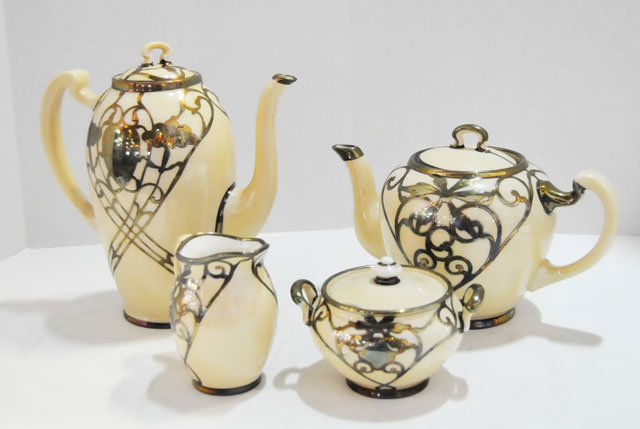 4 piece Lenox silver overlay coffee & tea set: 4 pieces. Cream colored porcelain with silver overlay, coffee pot approx. 9" x 8", teapot approx. 6.5" x 9", creamer 4" x 4", sugar 3.5" x 4.75". sugar & creamer have hairline cracks. From a Brooklyn,