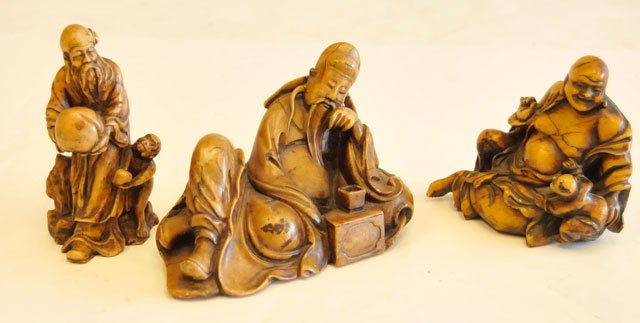 Lot of 3 soapstone figures: 1- "Reclining Man", approx. 4" H x 5.5" W. 1- "Seated Buddha with Child", approx. 4" H x 4.5" W. 1- "Man Holding Gourd with Child", approx. 4.25" H. Please read our terms of sale.