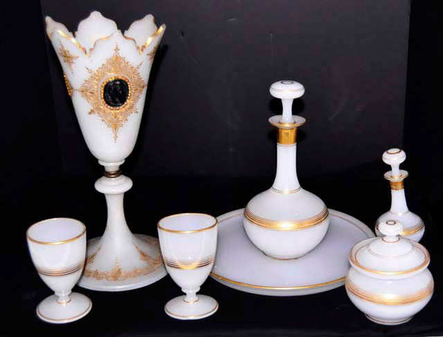 Early opaline glass vanity set & vase: 7 pieces in total. Including: 1- Round tray, approx. 11". 2- glasses, approx. 4.5". 1- Covered powder jar, approx. 5.5" H. 1- Perfume decanter, approx. 6.5" H. 1- Decanter vase, as is, approx. 10.5".